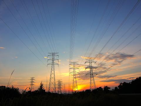 Three Black Metal Electricity Posts during Golden Hour